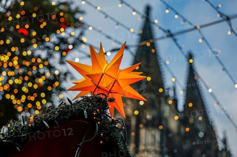 Christmas market at Cologne Cathedral, shining yellow star on a Christmas stall with fairy lights and Cologne Cathedral in the background, Roncalliplatz, Cologne, North Rhine-Westphalia, Germany, Europe