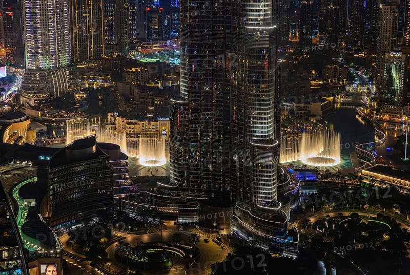 A picture of the Dubai Fountain Show, at night, and the bottom of the Burj Khalifa, next to other Downtown Dubai buildings
