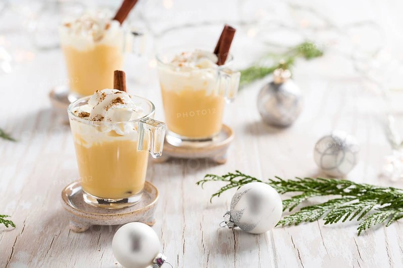 Eggnog with cinnamon and nutmeg for Christmas and winter holidays. With Xmas decorations on wooden background