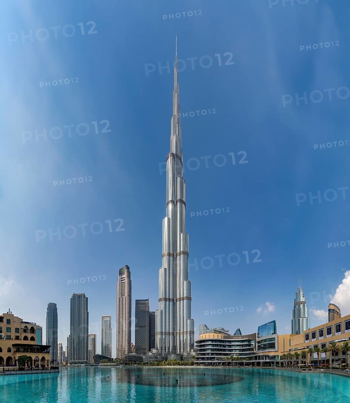 A picture of the Burj Khalifa towering the nearby Downtown Dubai buildings and the blue waters of the Burj Khalifa Lake