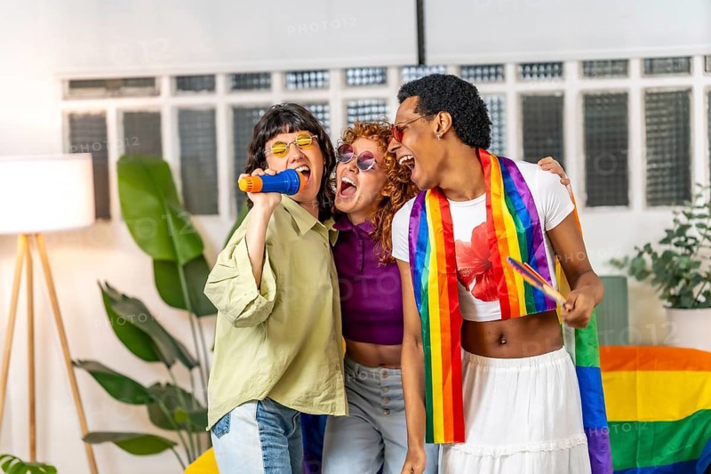 Multi-ethnic and gender diverse lgbt friends singing karaoke during pride party at home