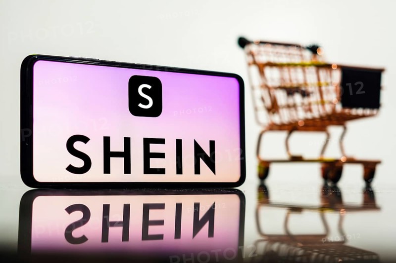 In this photo illustration, the Shein logo seen displayed on a smartphone along with a shopping cart