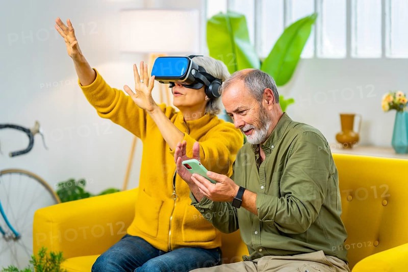 Elderly couple with playing VR game together using virtual reality goggles and mobile phone