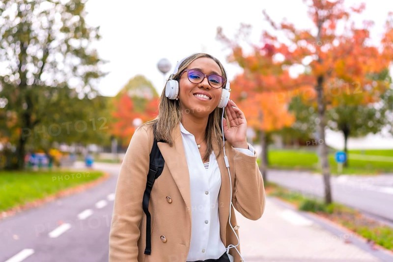 Latin blonde confident businesswoman listening to music walking along the city