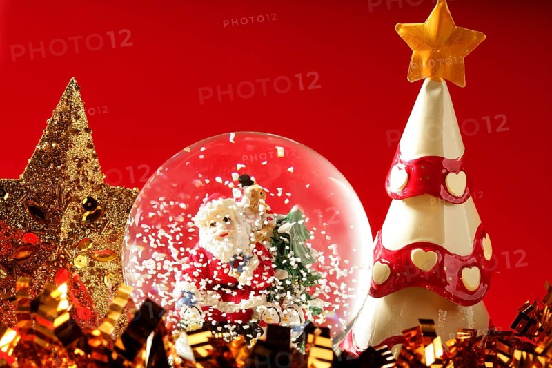 Santa claus figurine on a glass snowing ball, red background studio shot