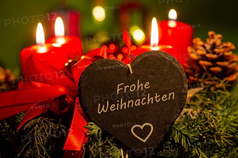 Christmas greetings: Heart with the inscription FROHE WEIHNACHTEN in front of Christmas decorations