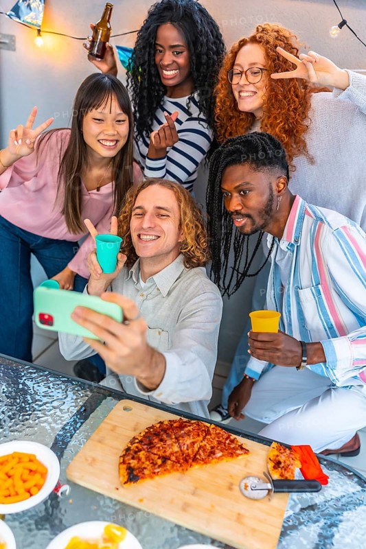 Multi-ethnic friends taking selfie celebrating party eating snacks and drinking in a urban rooftop
