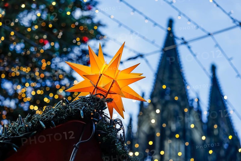 Christmas market at Cologne Cathedral, shining yellow star on a Christmas stall with fairy lights and Cologne Cathedral in the background, Roncalliplatz, Cologne, North Rhine-Westphalia, Germany, Europe