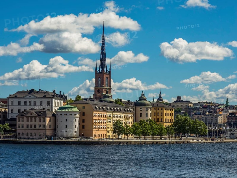 Church tower and historic buildings on the waterfront under a blue sky with clouds, archipelago, stockholm, sweden