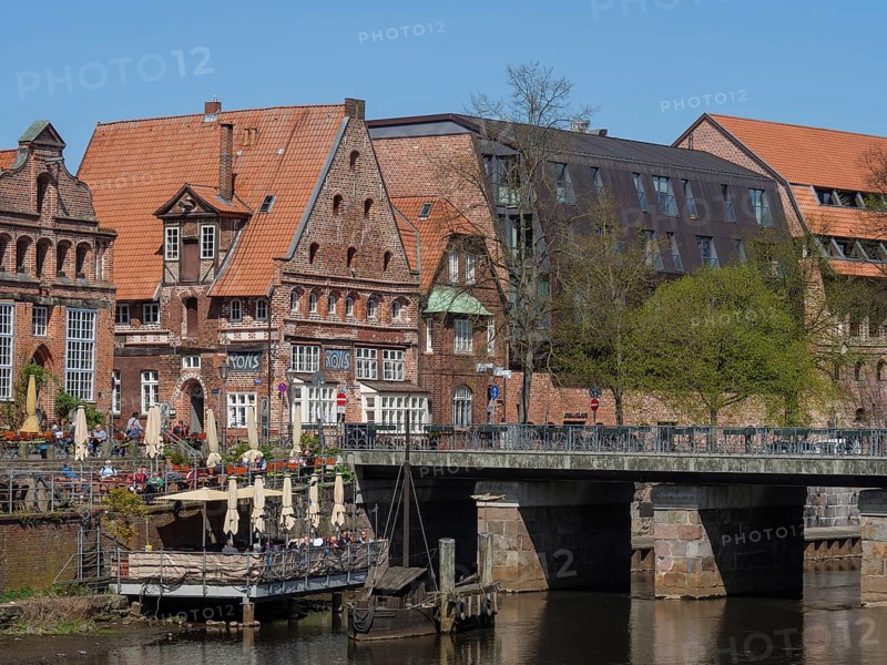 Charming half-timbered houses flank a river, while a bridge leads to a historic neighbourhood, lüneburg, germany