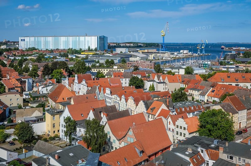 Wismar, Mecklenburg-Western Pomerania, Germany, city view of Wismar's old town centre, behind MV Werften Wismar-Rostock-Stralsund. The cruise ship shipyard still employs around 700 people, compared to 1, 300 in front of the shipbuilding crisis, making it one of Wismar's largest employers. The newly built facilities in Wismar also include the covered building dock, whose hall is 72 metres high, 155 metres wide and over 395 metres long. The shipyard has belonged to the Malaysian-Chinese shipping company Genting Hong Kong since March 2016. Genting founded the new MV Werften, which in future will comprise the Wismar, Warnemünde and Stralsund sites with a total of around 1, 700 employees The shipyard group filed for insolvency in January 2022 and the shipyard was sold to Thyssenkrupp Marine Systems as a result in June 2022, Europe