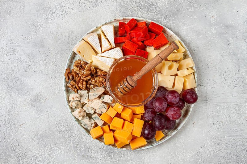 Appetizer, assorted cheese, with nuts and honey, on a round plate, top view, no people