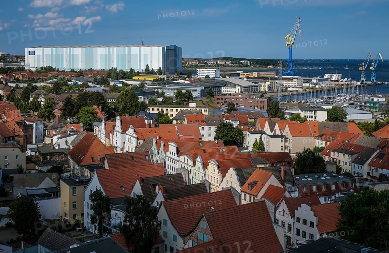 Wismar, Mecklenburg-Western Pomerania, Germany, city view of Wismar's old town centre, behind MV Werften Wismar-Rostock-Stralsund. The cruise ship shipyard still employs around 700 people, compared to 1, 300 in front of the shipbuilding crisis, making it one of Wismar's largest employers. The newly built facilities in Wismar also include the covered building dock, whose hall is 72 metres high, 155 metres wide and over 395 metres long. The shipyard has belonged to the Malaysian-Chinese shipping company Genting Hong Kong since March 2016. Genting founded the new MV Werften, which in future will comprise the Wismar, Warnemünde and Stralsund sites with a total of around 1, 700 employees The shipyard group filed for insolvency in January 2022 and the shipyard was sold to Thyssenkrupp Marine Systems as a result in June 2022, Europe