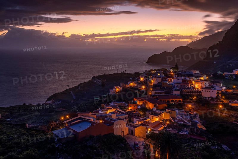 The village of Agulo shortly in front of sunrise. Houses and streets are still illuminated. View of the sea and the coast. Agulo, La Gomera, Canary Islands, Spain, Europe