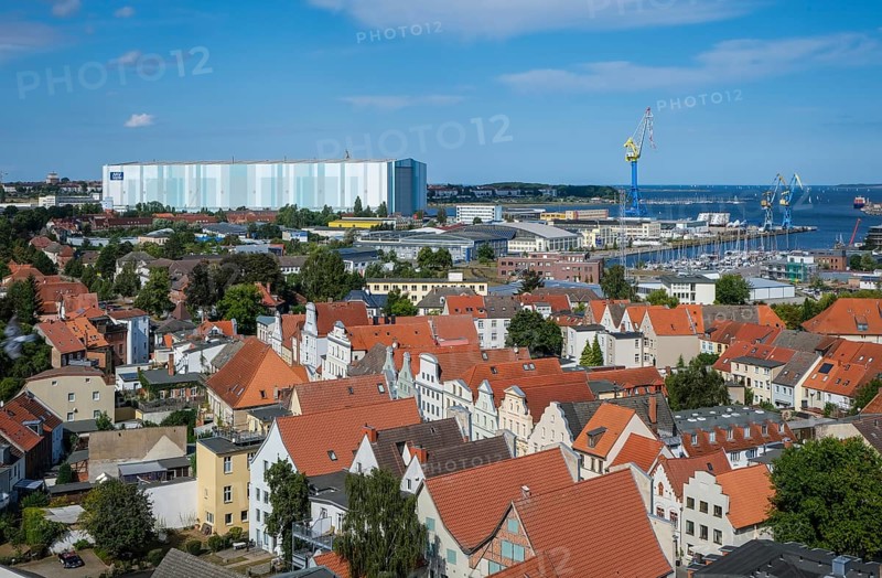 Wismar, Mecklenburg-Western Pomerania, Germany, city view of Wismar's old town centre, behind MV Werften Wismar-Rostock-Stralsund. The cruise ship shipyard still employs around 700 people, compared to 1, 300 in front of the shipbuilding crisis, making it one of Wismar's largest employers. The newly built facilities in Wismar also include the covered building dock, whose hall is 72 metres high, 155 metres wide and over 395 metres long. The shipyard has belonged to the Malaysian-Chinese shipping company Genting Hong Kong since March 2016. Genting founded the new MV Werften, which in future will comprise the Wismar, Warnemünde and Stralsund sites with a total of around 1, 700 employees The shipyard group filed for insolvency in January 2022 and the shipyard was sold to Thyssenkrupp Marine Systems as a result in June 2022, Europe