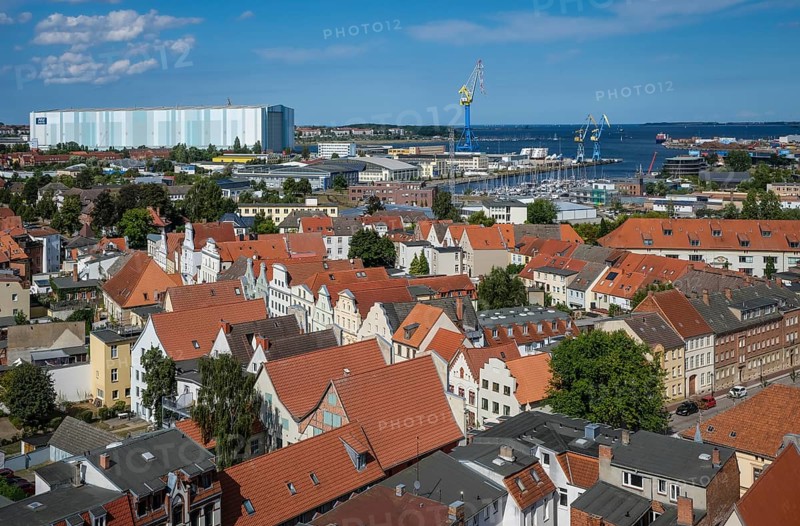 Wismar, Mecklenburg-Western Pomerania, Germany, city view of Wismar's old town centre, behind MV Werften Wismar-Rostock-Stralsund. The cruise ship shipyard still employs around 700 people, compared to 1, 300 in front of the shipbuilding crisis, making it one of Wismar's largest employers. The newly built facilities in Wismar also include the covered building dock, whose hall is 72 metres high, 155 metres wide and over 395 metres long. The shipyard has belonged to the Malaysian-Chinese shipping company Genting Hong Kong since March 2016. Genting founded the new MV Werften, which in future will comprise the Wismar, Warnemünde and Stralsund sites with a total of around 1, 700 employees The shipyard group filed for insolvency in January 2022 and the shipyard was sold to Thyssenkrupp Marine Systems as a result in June 2022, Europe