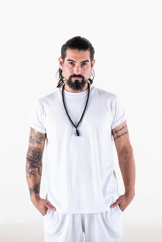 Portrait of a man dressed in white yoga clothes over white background while looking at camera. Studio shot