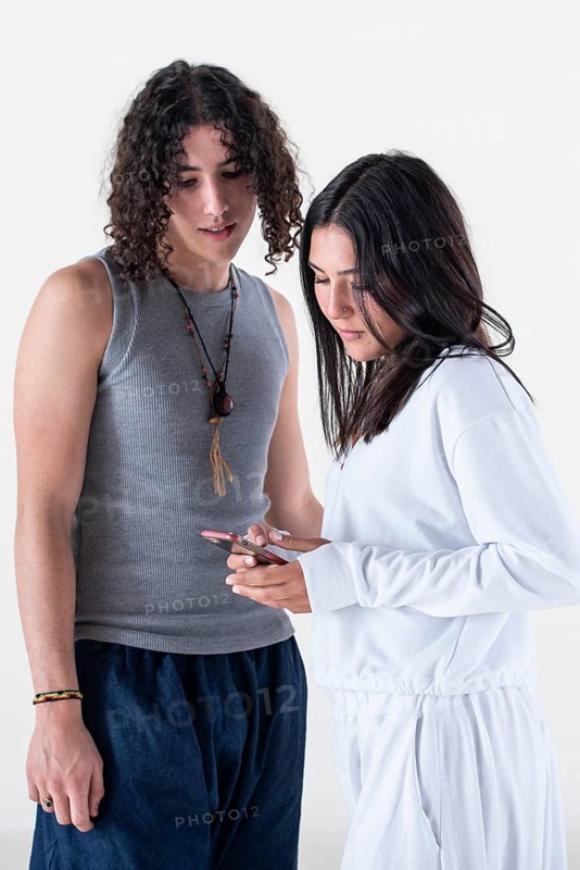 Portrait of a young couple dressed in yoga clothes looking a smartphone over white background. Studio shot