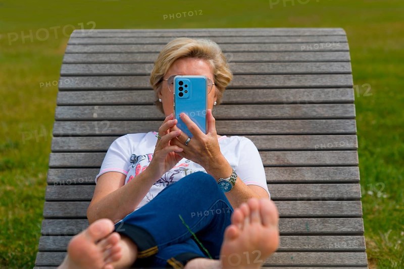 Woman on a wooden couch holding her mobile phone