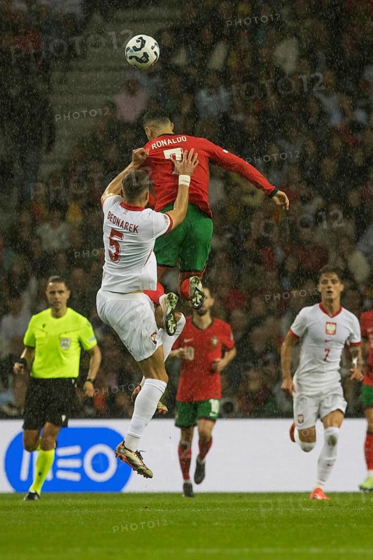 Football match, captain Cristiano RONALDO CR7 Portugal in red heading a ball three times as high as his opponent Jan BEDNAREK Poland left, referee Donatas RUMSAS Lithuania and right Kacper URBANSKI Poland watch the scene in amazement, Estadio do Dragao, Porto, Portugal, Europe