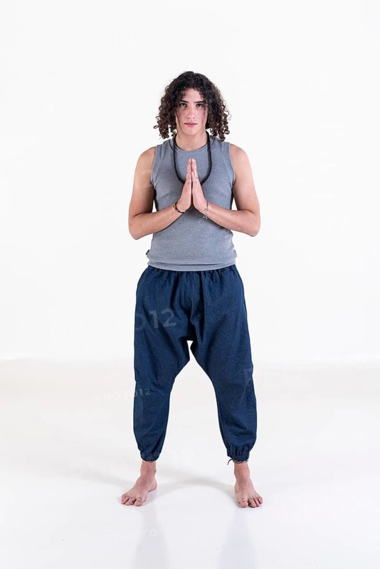 Young man clasping hands while looking at camera over white background. Meditation concept. Studio shot