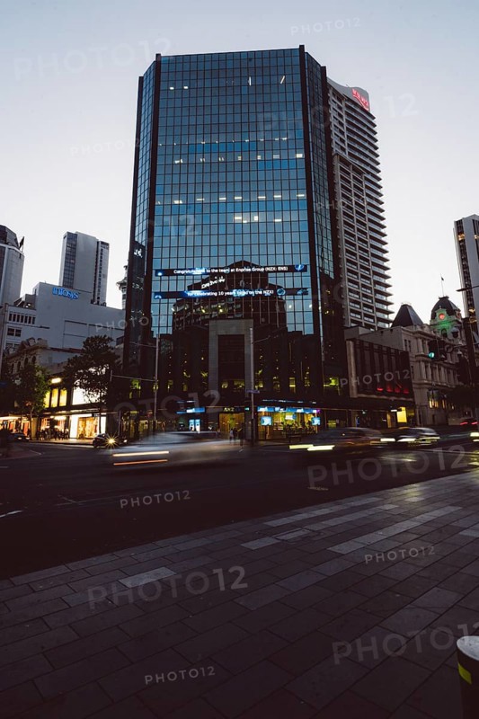 High-rise building with reflective glass façade at dusk, city lights and passing cars, new Zealand stock exchange, Auckland, New Zealand, Oceania