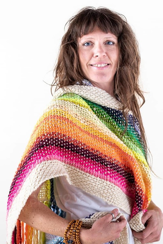 Smiling woman looking at camera, wearing a colored pashmina over a white background. Studio Shot