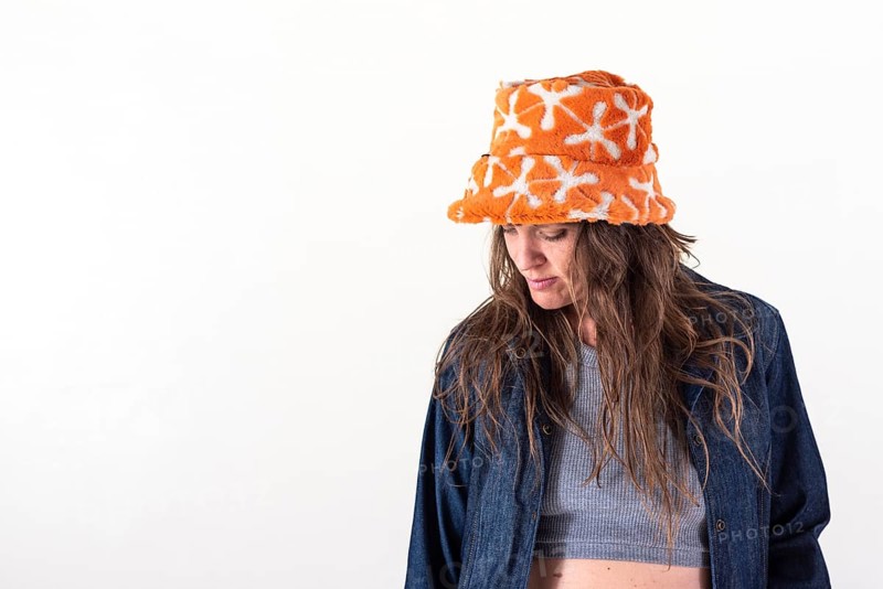 Portrait of a woman looking down, wearing a hat over a white background. Copy Space. Studio Shot