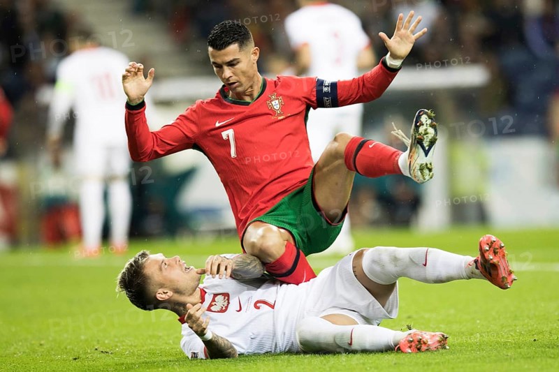 Football match, captain Cristiano RONALDO CR7 Portugal on the stomach of Kamil PIATKOWSKI Poland kneeling with his left leg and falling backwards with his hands outstretched upwards, looking at his opponent, Kamil PIATKOWSKI Poland lying on the ground on the grass screaming with his left leg up and direct eye contact with Cristiano RONALDO Portugal, Estadio do Dragao, Porto, Portugal, Europe