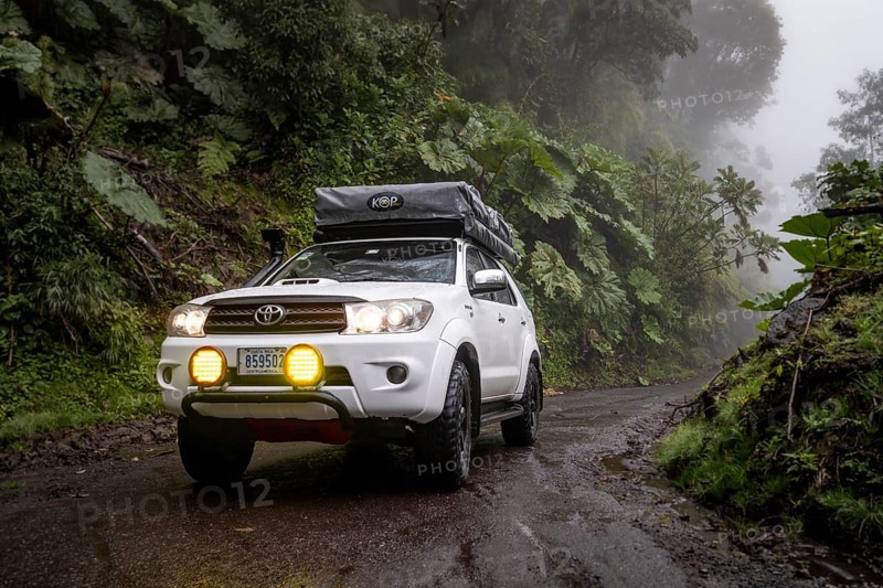 Off-road vehicle in the fog in the rain, with fog lights on a narrow road, dense vegetation on a mountain road, near Esperanza, Cartago province, Costa Rica, Central America