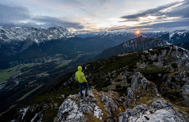 View Mountain panorama with Wetterstein mountains and Zugspitze, at sunset with sun star, mountaineer at the summit of the Kramerspitz, in autumn, Ammergau Alps, in autumn, Bavarian Prealps, Bavaria, Germany, Europe