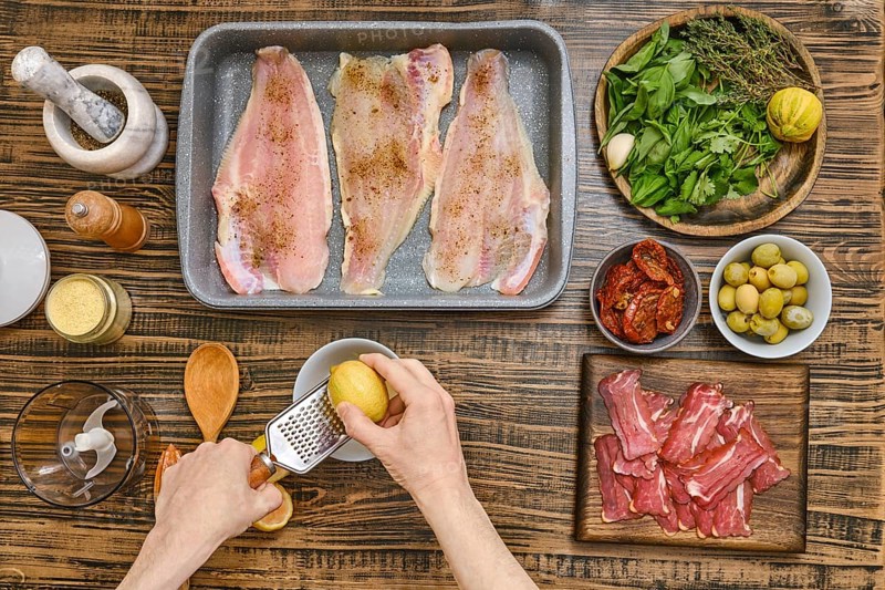 Hands rub the zest of lemon for sauce to cook juicy fish