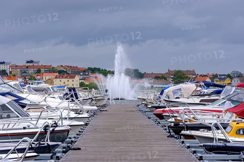 Boat mooring with boats in front of the island of Stakholmen with a view of the water fountain in the city harbour of Karlskrona, Blekinge län, Sweden, Europe