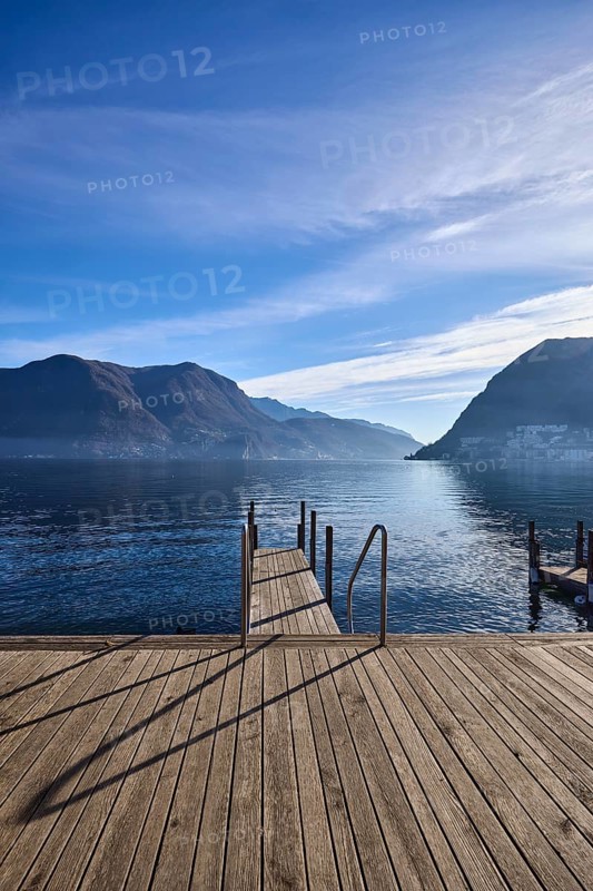 Jetty, wooden planks, stainless steel railing, frog perspective, lake, jetty, mountain landscape, haze, backlight, blue sky, cirrus clouds, veil clouds, Lake Lugano, Lugano, district of Lugano, canton of Ticino, Switzerland, Europe
