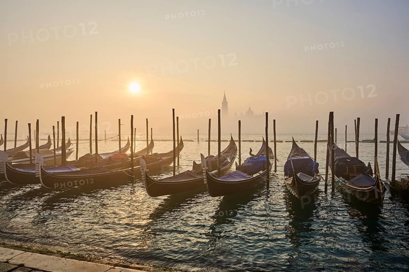 View from 'Colonna di San Marco e San Teodoro' on the gondolas lying in the water with the church 'Giorgio Maggiore' in the background at sunrise in Venice on a foggy morning in winter, Italy, Europe