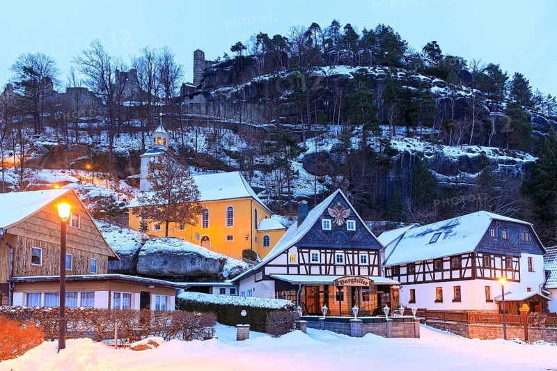 Striking half-timbered houses and mountain church in front of Mount Oybin with ruins, snow and twilight, Zittau Mountains, Saxony, Germany, Europe