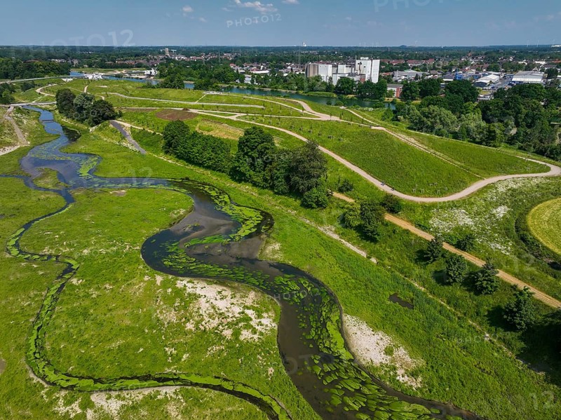 Castrop-Rauxel, Recklinghausen, North Rhine-Westphalia, Germany, EMSCHERLAND adventure park at the Emscher-RHK water crossing. View up the Emscher towards the future vineyard, the Rhine-Herne Canal and the industrial estate behind it. EMSCHERLAND, an approximately 30-hectare water and nature adventure park at the water crossroads of the Rhine-Herne Canal (rear) and the renaturalised Emscher (centre) on the border between Recklinghausen and Castrop-Rauxel. The ecological focus at the confluence of Suderwicher Bach (left) and Emscher (centre) will also be a future garden for the International Garden Exhibition 2027. Before the renaturation, the Emscher river system was an open, above-ground wastewater channel, a combined sewer with surface water and wastewater. Where the Emscher, the Suderwicher Bach and the Rhine-Herne Canal meet, an inter-municipal adventure park has been created in recent years on an area of around 30 hectares. The park's facilities include, Europe