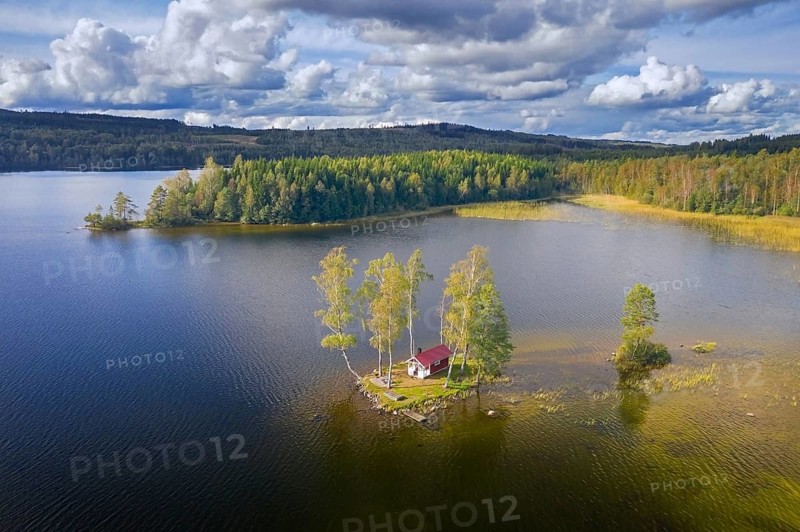 Aerial view over small traditional red wooden cabin on tiny island in lake in autumn, fall, Värmland, west-central Sweden, Scandinavia