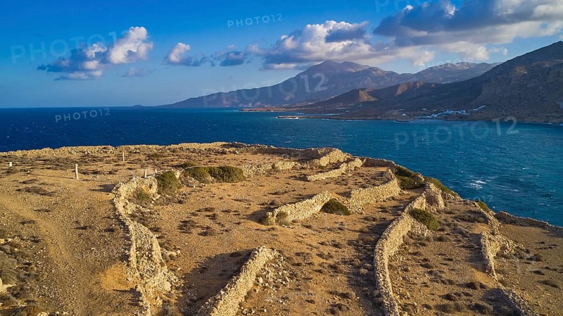 Drone shot, Archaeological excavation site, landscape of ruins by the sea with distant view of mountains in the background, acropolis hill, ruins of an acropolis, Arkasa, west coast, Karpathos, Dodecanese, Greek Islands, Greece, Europe