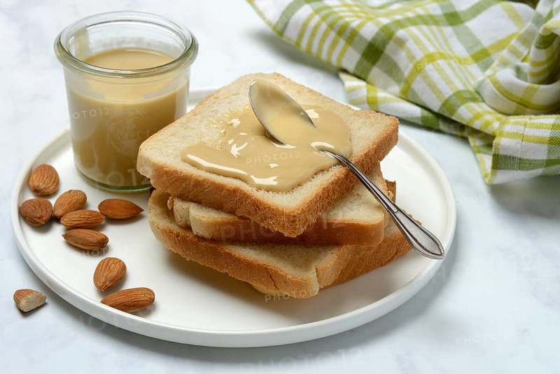 Almond cream on toast, almonds and spoon