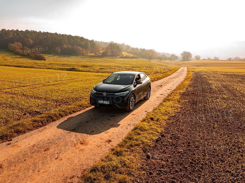 A car drives along a remote country lane through an autumn landscape full of fields, electric car VW ID5, Deer Carsharing, Gechingen, Black Forest, Germany, Europe