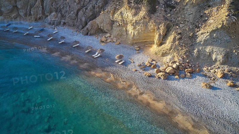 Pebble beach with clear blue waves and rocky coastline. Silence and seclusion, beach loungers, parasols, drone shot, evening light, Araki Beach, south-west coast, Karpathos, Dodecanese, Greek Islands, Greece, Europe