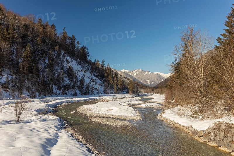 The Riss creek flowing through a snow covered landscape in the Eng valley. Sunny day with blue sky