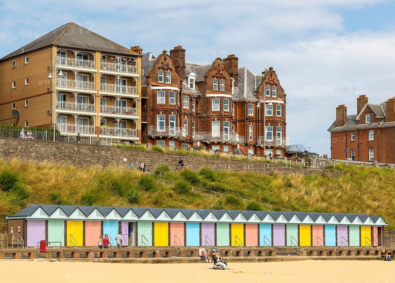 Colourful beach huts and historic clifftop buildings, South Beach, Lowestoft, Suffolk, England, UK