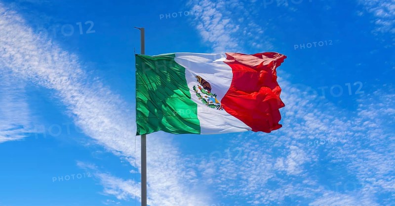 Los Cabos, Mexico, Mexican tricolor national striped flag proudly waving at mast in the air with Aztec symbol for Tenochtitlan, Central America