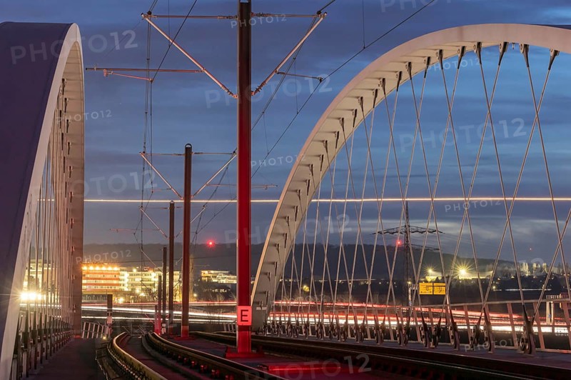 Modern light rail bridge made of carbon from Stuttgarter Straßenbahnen AG over the motorway in the evening. Traces of light from road traffic and from an aeroplane landing at nearby Stuttgart Airport. Stuttgart, Baden-Württemberg, Germany, Europe