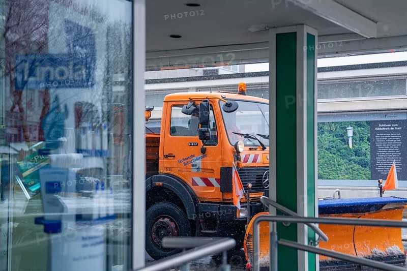 Orange snow clearing vehicle in front of a shop window in a wintry environment, Sindelfingen, Germany, Europe
