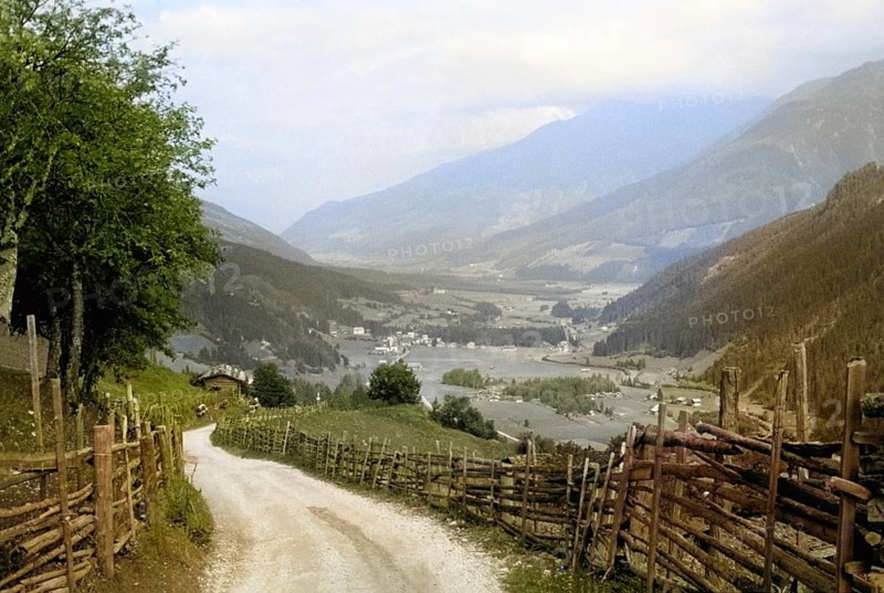 Country road lane leading to villages rural settlement in Alpine mountain valley Tyrol, Austria, Europe, 1956 colourised Ektachrome slide, Europe