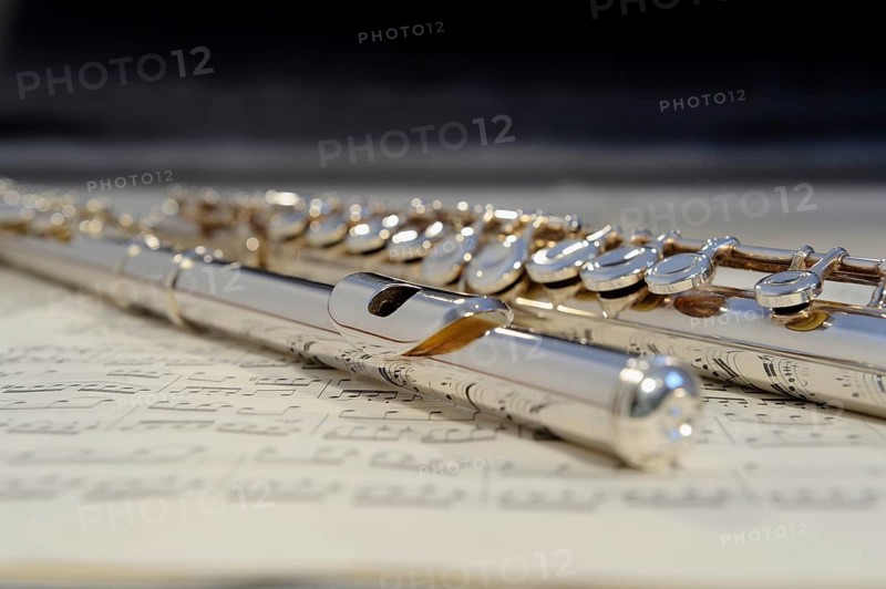 Transverse flute lying on a sheet of music, musical instrument in silver