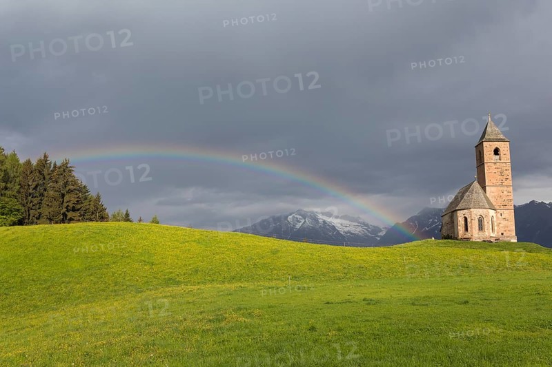 Church St. Kathrein, 39010 Hafling, Italy with a rainbow in the background. The church is from the 13 th century